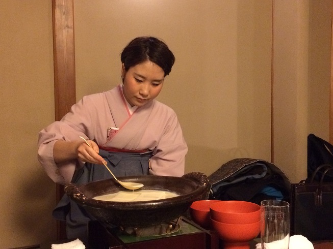 traditionally-dressed waitress ladles out tofu soup