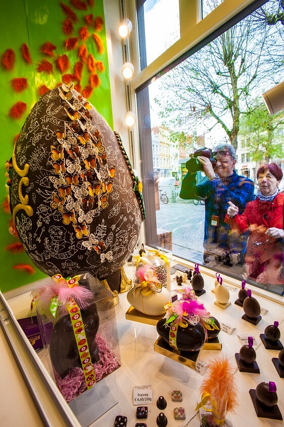 people looking at chocolate in a shop window in bruges